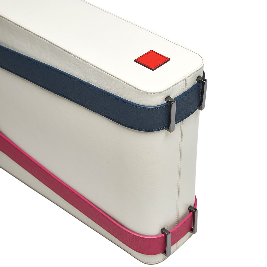 A product photo showing the bottom of a color-blocked off-white leather tote handbag. The tote has a structured rectangular shape and flat handles. This is the Tomoli Kora tote in eclectic ivory aria leather. This bag can be used as a work bag or an everyday bag.