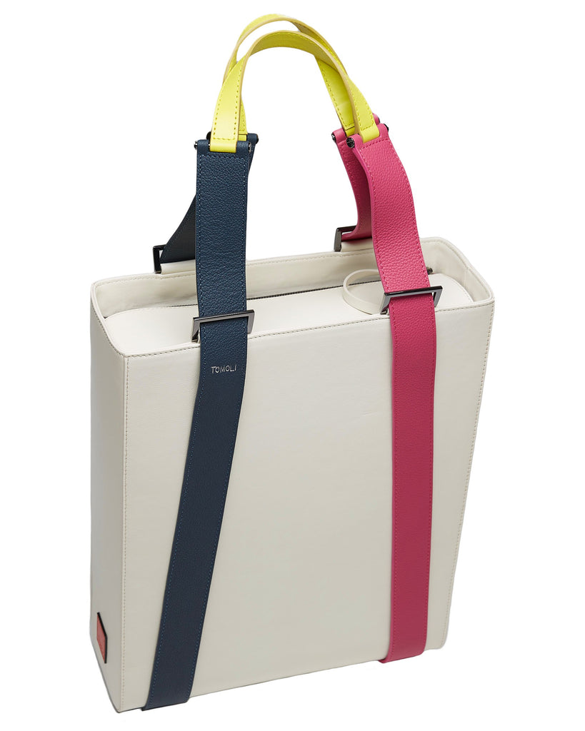 A product photo of a color-blocked off-white leather tote handbag. The tote has a structured rectangular shape and flat handles. This is the Tomoli Kora tote in eclectic ivory aria leather. This bag can be used as a work bag or an everyday bag.