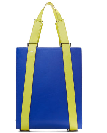 A product photo of a bright blue leather tote bag. The tote bag has a structured rectangular briefcase shape and color-blocked neon green leather straps. This is the front view of the Tomoli Kora large convertible leather tote in lime blue. The bag can fit a laptop and can be styled for work or to elevate casual outfits.