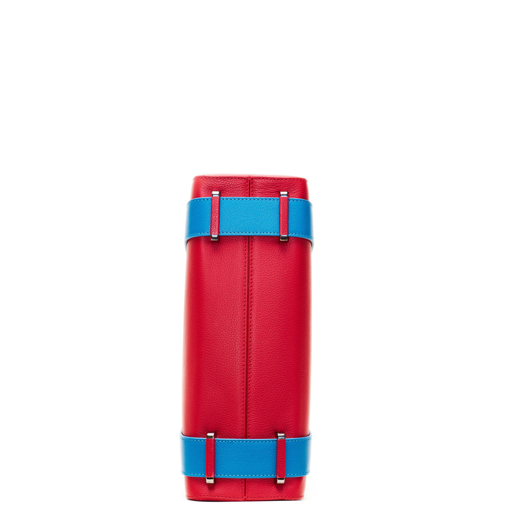 A product photo showing the bottom view of a red leather tote. The bottom shows a center seam and color-blocked blue straps. This is the Tomoli Kora large convertible leather tote in Sky Red.