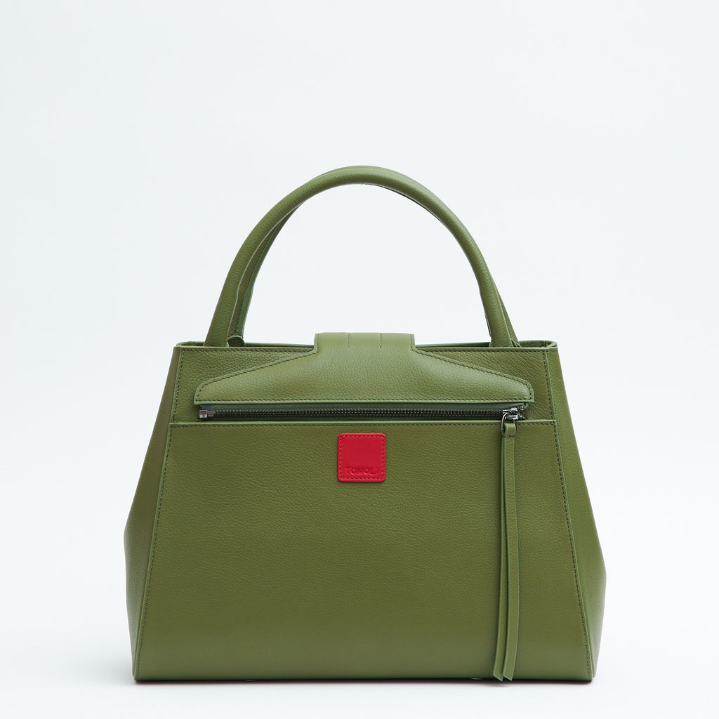 The product photo of an olive green leather handbag. The handbag has a classic trapeze shape with a back pocket, a zipper to interchange flaps, and top handles. This is the back view of the Tomoli Briffani Lean interchangeable tote handbag in Olive Green. This bag can be used as an everyday bag, a work tote, or even an oversized clutch.