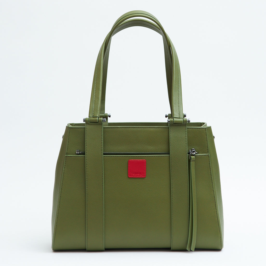The product photo of an olive green leather handbag. The handbag has a classic trapeze shape with a back pocket, a zipper to interchange flaps, and top handles. This is the back view of the Tomoli Briffani Orbit interchangeable tote handbag in Olive Green. This bag can be used as an everyday bag, a work tote, or even an oversized clutch.