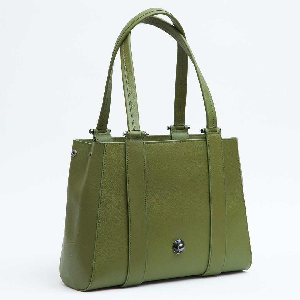 The product photo of an olive green tote leather handbag. The handbag has a classic trapeze shape with a back pocket, a zipper to interchange flaps, and top handles. This is the back view of the Tomoli Briffani Orbit interchangeable tote handbag in Olive Green. This bag can be used as an everyday bag, a work tote, or even an oversized clutch.