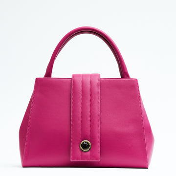 A product photo showing the front view of a colorful pink leather tote handbag. The handbag has a classic trapeze shape with pink top handles and a straight quilted flap closure in the middle. This is the Tomoli Briffani Lean interchangeable tote handbag in Fuchsia. This fashion bag can be used as an everyday bag, a work tote, or even an oversized clutch.