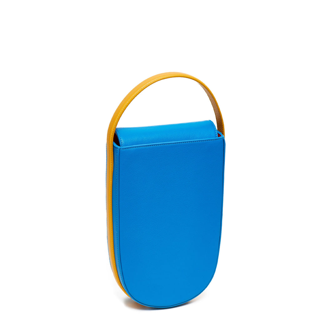 A colorful blue and yellow mini leather handbag. The handbag has an elongated rounded shape and an adjustable yellow top handle. The hardware is gunmetal. This is the front view of the Tomoli Fitini bag in Golden Sky.