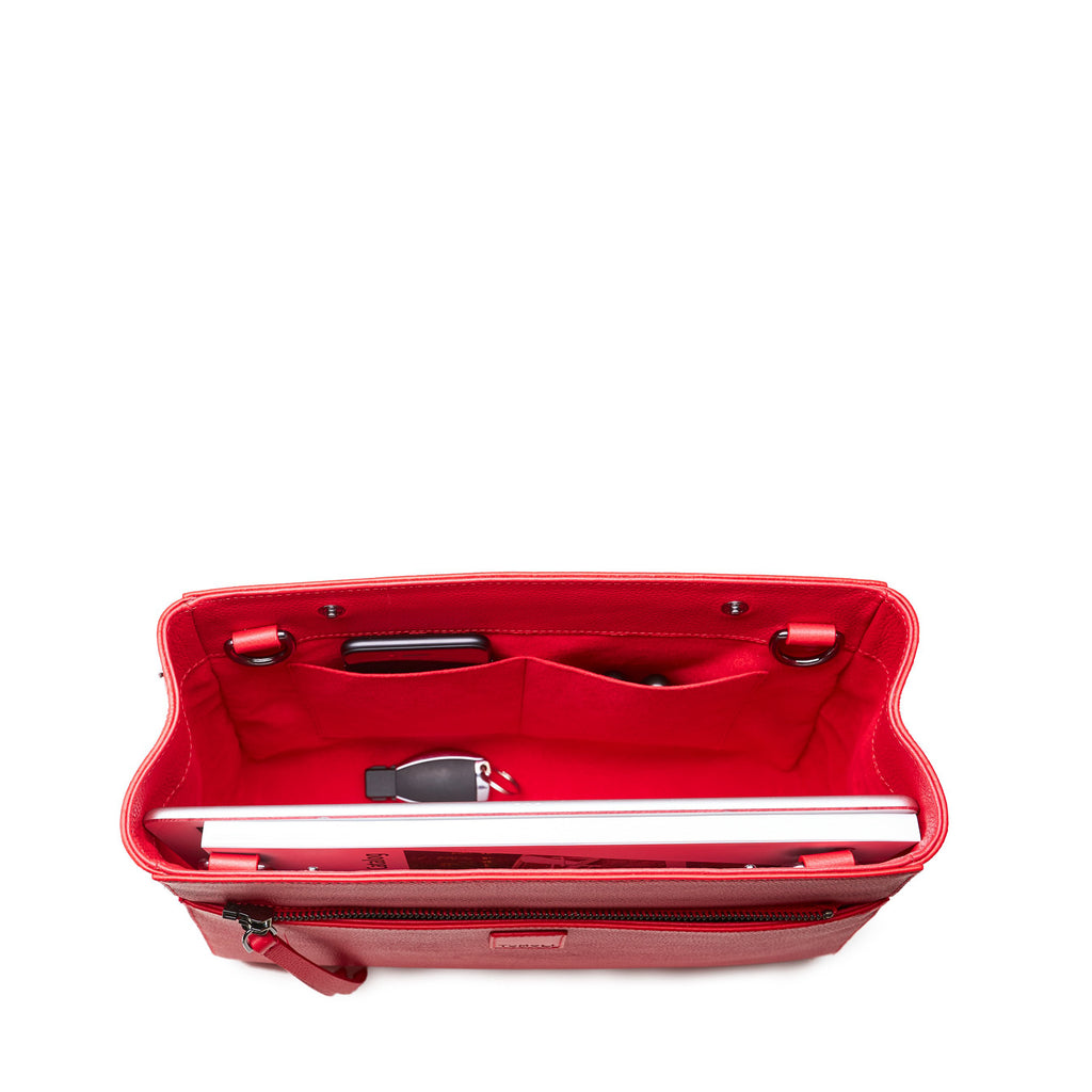 The product photo of a fashion handbag showing the interior of a red leather bag. The bag has a bright red lining made of alcantara microsuede material. This is the interior view of the Tomoli Briffani Jut handbag in Red. This bag fits a laptop and a large iPad Pro tablet.