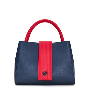 The product photo of a colorful red and blue leather handbag. The handbag has a classic trapeze shape with a straight quilted flap in the middle and top handles. This is the front view of the Tomoli Briffani Lean interchangeable tote handbag in Hot Denim. This bag can be used as an everyday bag, a work tote, or even an oversized clutch.