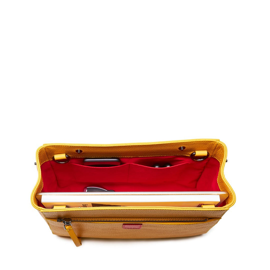 The product photo of a fashion handbag showing the interior of a yellow leather bag. The bag has a bright red lining made of alcantara microsuede material. This is the interior view of the Tomoli Briffani Jut handbag in Maize. This bag fits a laptop and a large iPad Pro tablet.