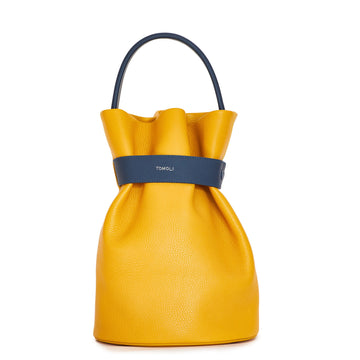 The product photo of a colorful fashion handbag showing a yellow leather bucket bag with a dark blue belt cinch and a dark blue top handle. This is the front view of the Tomoli La Bourse leather bucket bag in Shady Maize.